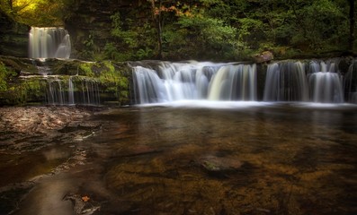 Obraz premium Sgwd Ddwli Isaf waterfalls on the river Neath, part of the waterfall country trail of falls, near Pontneddfechan in South Wales, UK. 