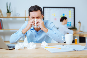 Frustrated brunette blowing his nose