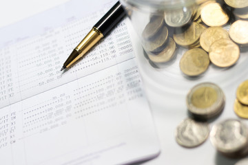 Gold pen and coins on bank account passbook. Concept of money saving and financial. Selective focus.