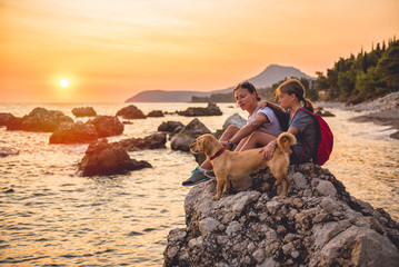 Mother and daughter with a dog hiking along the seashore - obrazy, fototapety, plakaty