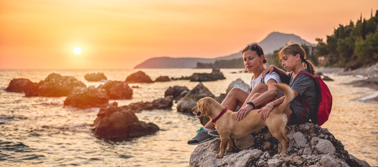 Mother and daughter with a dog hiking along the seashore