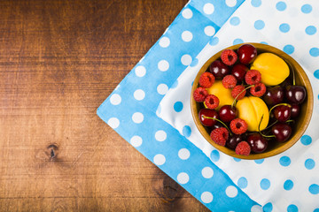 Ripe berries in a plate on a wooden table.