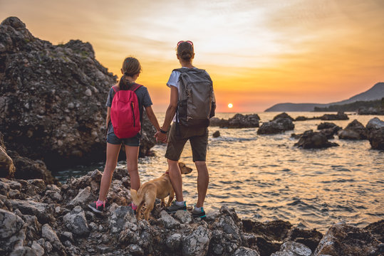 Mother and daughter with a dog hiking along the seashore