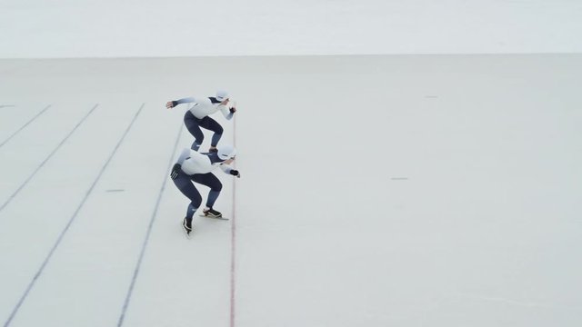 Slow motion of professional speed skaters in spandex full-body covering suits racing on ice