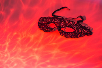 Venetian black mask on red flaming background