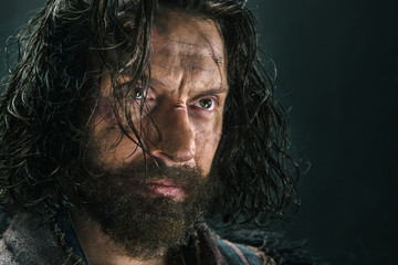 Portrait of a brutal bald-headed viking in a battle mail posing against a black background.