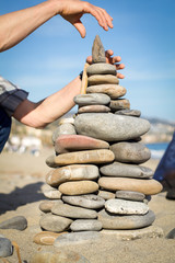 man's hands makes pyramid of stones