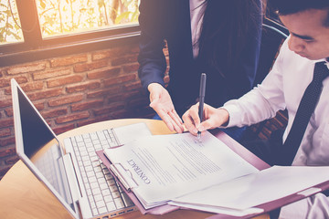 secretary showing document to her boss for signature in the office