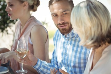 Happy friends interacting while having glass of wine
