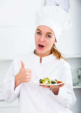 girl in chef's hat and white coat showing salad