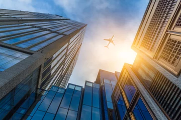 Photo sur Plexiglas Avion Tall city buildings and a plane flying overhead.