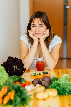 The young happy brunette woman with the fresh vegetables on the home kitchen. Healthy eating, cooking, food, dieting and people concept.