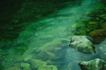 Fototapeta na wymiar Spooky rocks covered with moss in dark green water (horror concept)