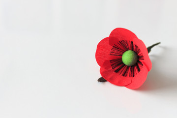 red poppy flower brooch on white table with soft-focus and over light in the background