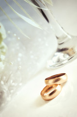 Two gold wedding rings on a light background