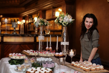 festive table with sweets and a variety of sweet snacks against the backdrop of  a girl confectioner