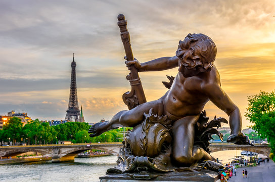 Sculpture on the bridge of Alexander III with the Eiffel Tower in the background at sunset in Paris, France.