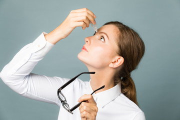 Young woman applying eye lotion.