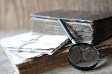 Old books on a wooden table and magnifier