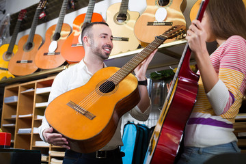 Adult couple choosing acoustic guitar in shop