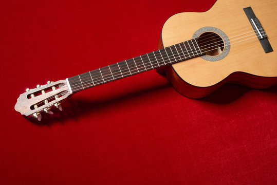 acoustic guitar on red velvet fabric, closeup object