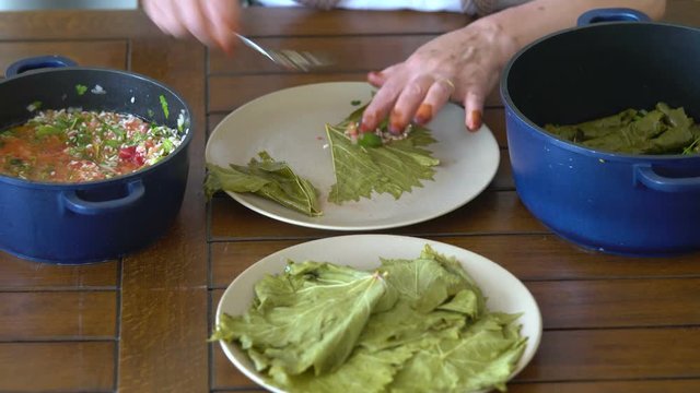 Turkish woman making Sarma - Traditional Turkish food. Grape leaves stuffed with rice and minced meat.