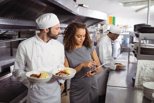 Chefs discussing menu on clipboard