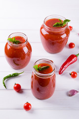 Tomato sauce, ketchup in glass jar and ingredients on a white background 