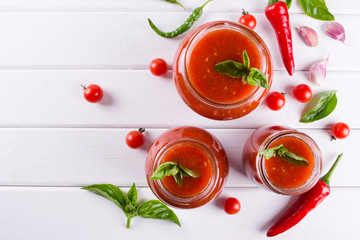 Tomato sauce, ketchup in glass jar and ingredients on a white background 