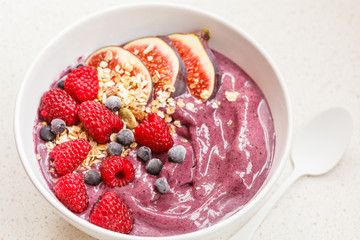 Smoothie bowl (blueberry, acai) with figs, raspberries and granola.