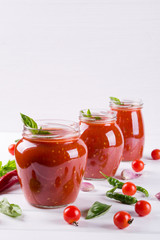 Fototapeta na wymiar Homemade preserved ketchup in glass jars. On a white background