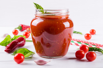 Fototapeta na wymiar Spicy sweet tomato sauce with garlic, pepper and herbs in a glass jars.