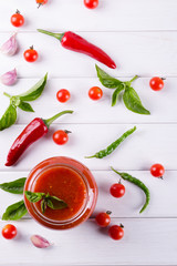 Spicy sweet tomato sauce with garlic, pepper and herbs in a glass jars.
