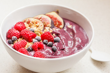 Smoothie bowl (blueberry, acai) with figs, raspberries and granola.