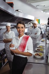 Fototapeta na wymiar Waitress standing with kitchen staff in commercial kitchen