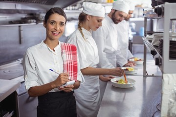Portrait of waitress standing with notepad