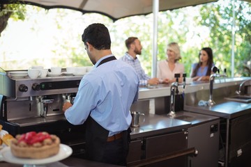 Waiter using tamper to press ground coffee into a portafilter