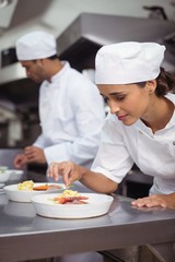 Female chef garnishing food in kitchen