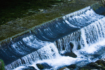 Small dam with water flowing rapids. Seen as lines and patterns with foam.