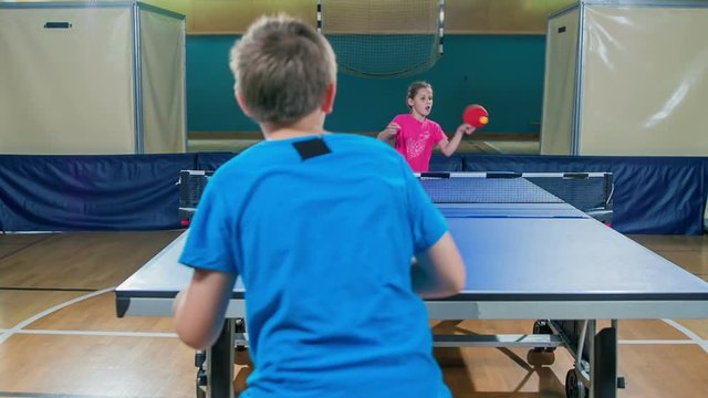 Two young students are playing table tennis in a school gym and they're both doing really well.