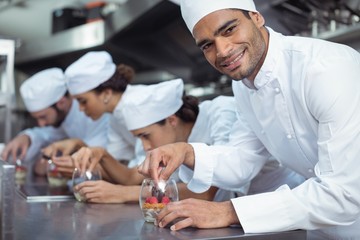 Fototapeta na wymiar Chefs finishing dessert in glass at restaurant
