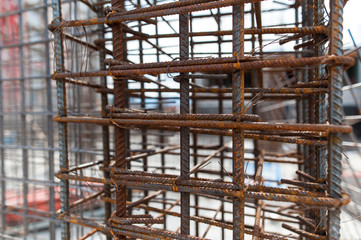 Fototapeta na wymiar Reinforcement net of concrete in the construction site, metal rods for strength with a building under construction on the background