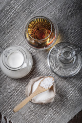 Cognac in a glass goblet, milk, water, sugar and salt in wooden spoon on the old wooden table and linen napkin. Top view. Toned