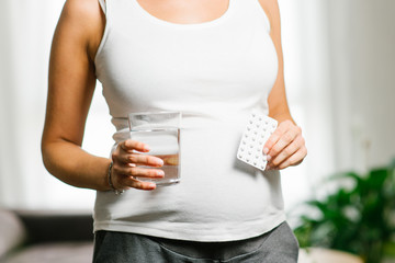 Pregnancy healthy concept. Pregnant woman holding folic acid supplement blister.