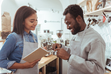 Female barista making notes while her colleague scrutinizing portafilter
