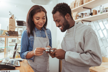 Pleasant smiling baristas scrutinizing portafilter