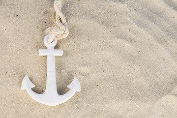 A white anchor in the sand on the beach
