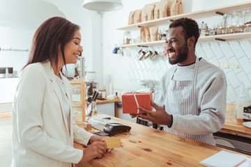 Smiling barista giving his customer a box with order