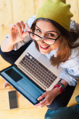 Hipster woman sitting on the floor using a laptop and mobile phone