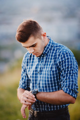Portrait of a stylish man with a clock in a plaid hipster shirt on a blurred background. copyspace